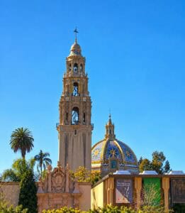 California Tower and its colorful blue, yellow, and white tiled dome rising above the trees in Balboa Park, San Diego.